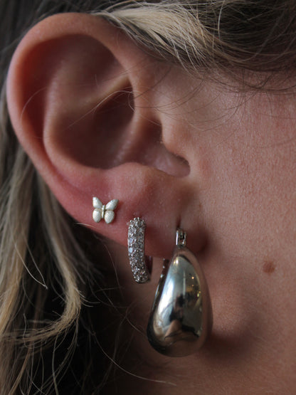 Silver earring stack featuring a bold chunky silver hoop, dainty silver huggie hoop and tiny butterfly stud earring