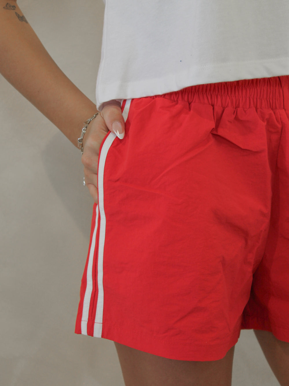 Red nylon track shorts with white stripes and pockets